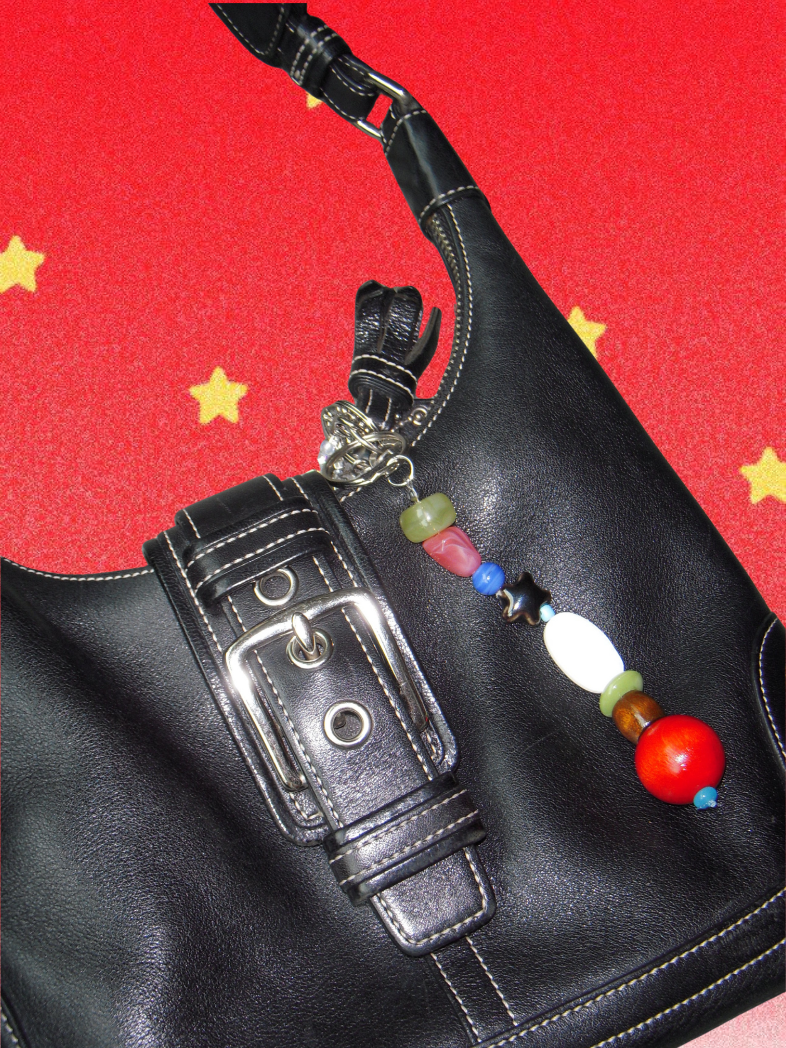 Colorful bag charm with charms on a black back against a pink background