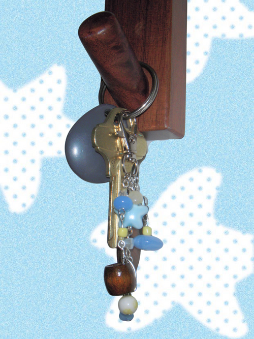 Keychain with decorative elements on a wooden stick against a light blue background