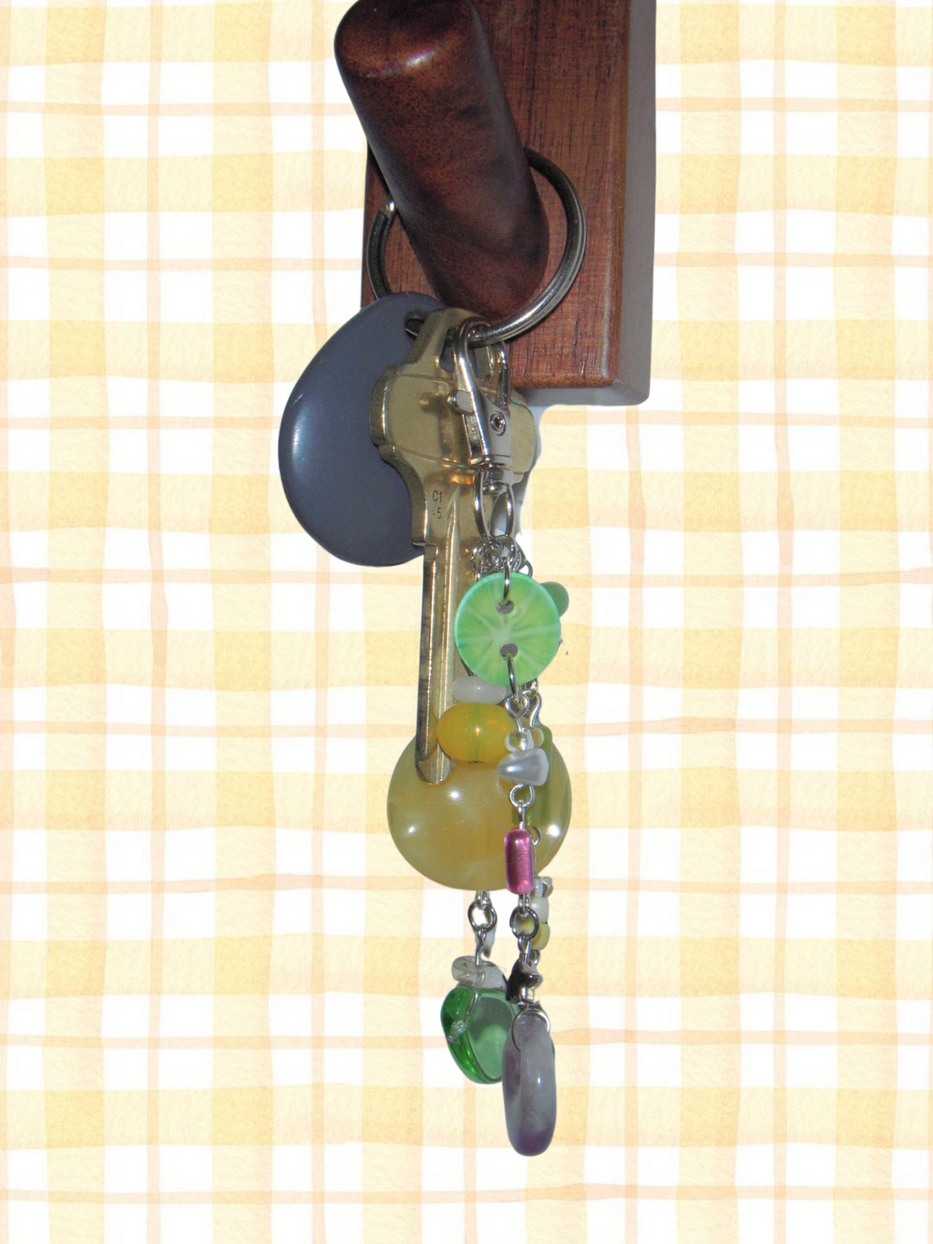 Decorative keychain with colorful beads hanging from a wooden key holder on a checkered background