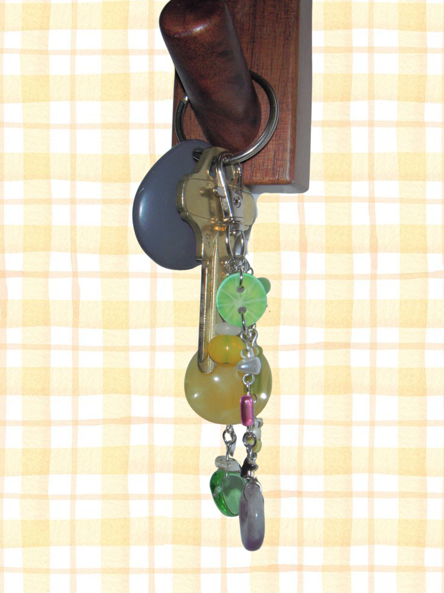 Decorative keychain with colorful beads hanging from a wooden key holder on a checkered background