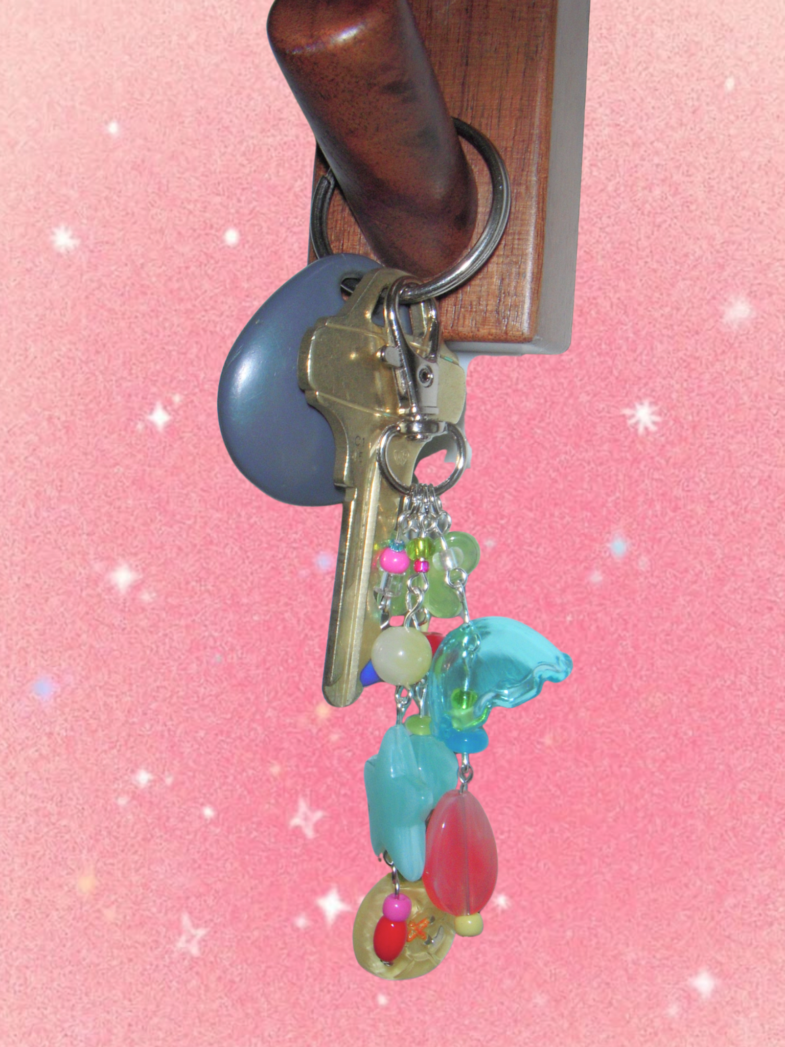 Keychain with colorful charms on a pink background.