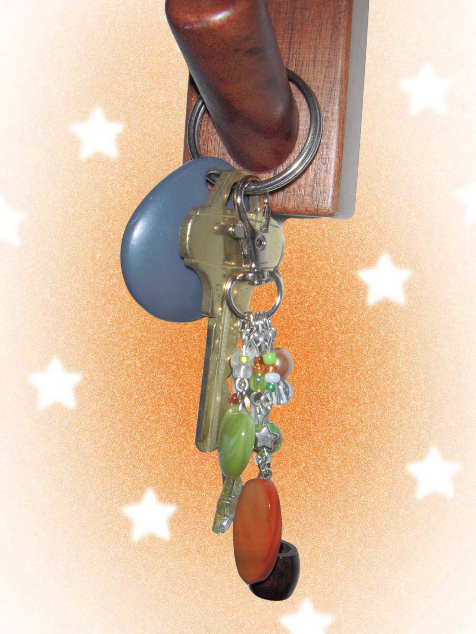 Keychain with colorful charms attached to a key on a wooden holder against a starry background.