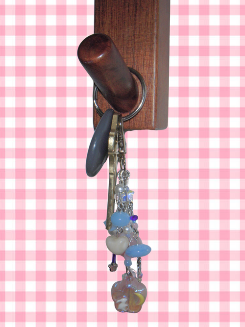 Wooden key holder with keychain on a pink and white checkered background